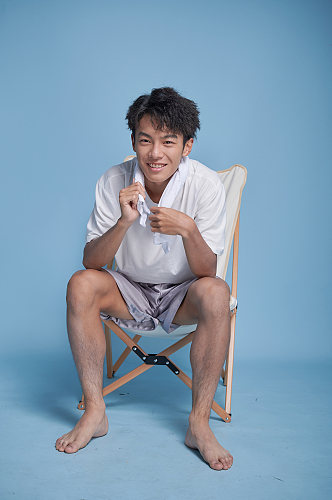 夏季男生泳装坐沙滩椅摄影图