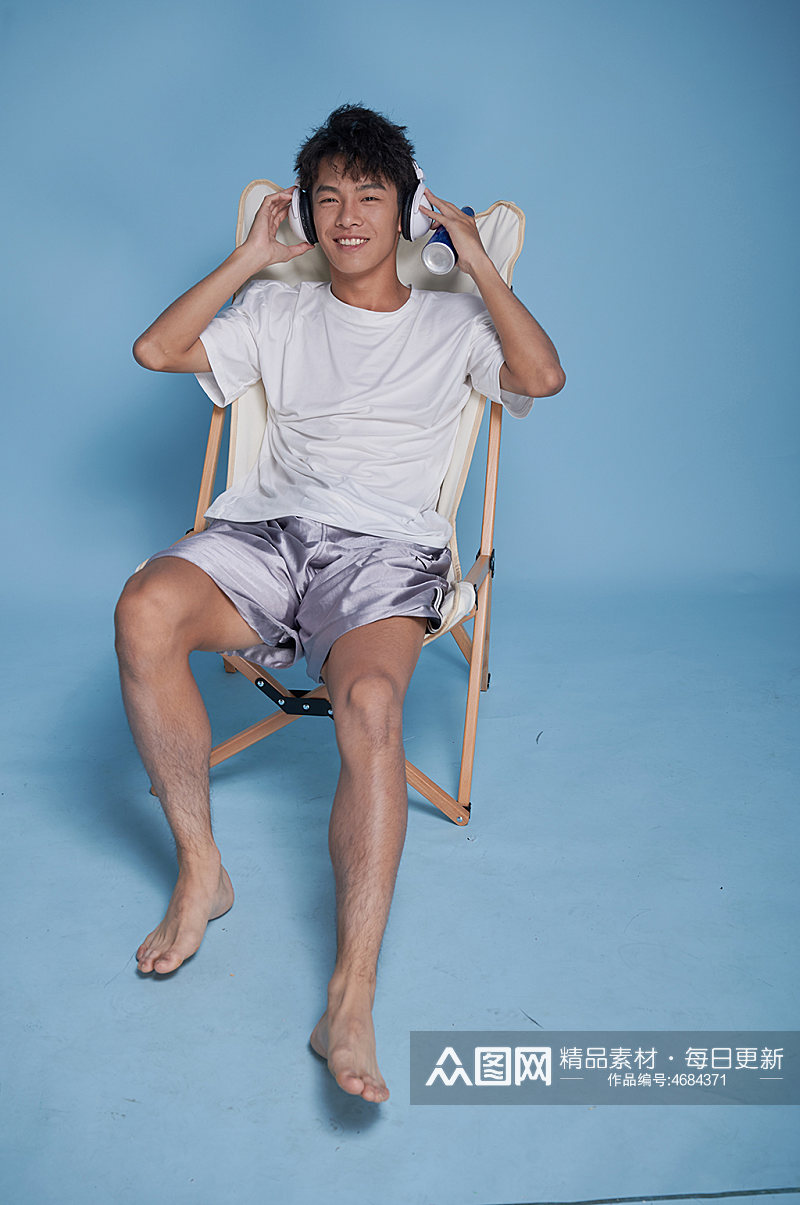 夏季男生听歌泳装坐沙滩椅摄影图素材