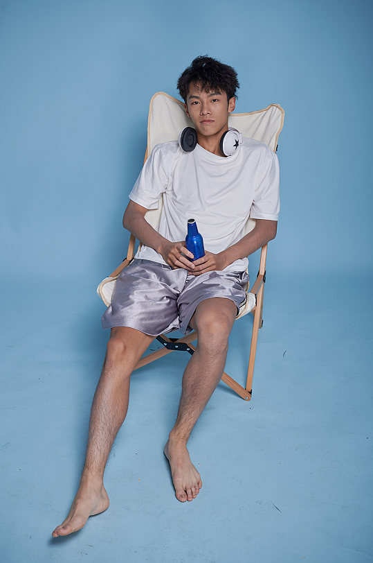 夏季男生听歌泳装坐沙滩椅摄影图