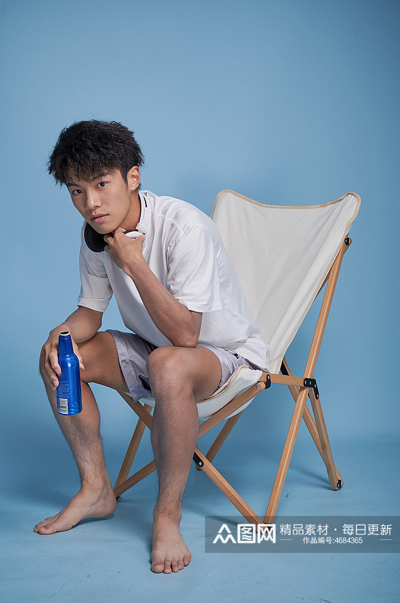 夏季男生喝啤酒泳装坐沙滩椅摄影图素材