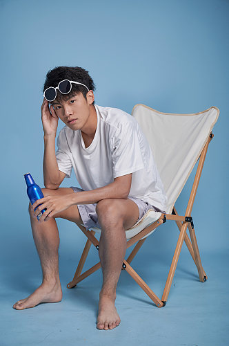夏季男生喝啤酒泳装坐沙滩椅摄影图