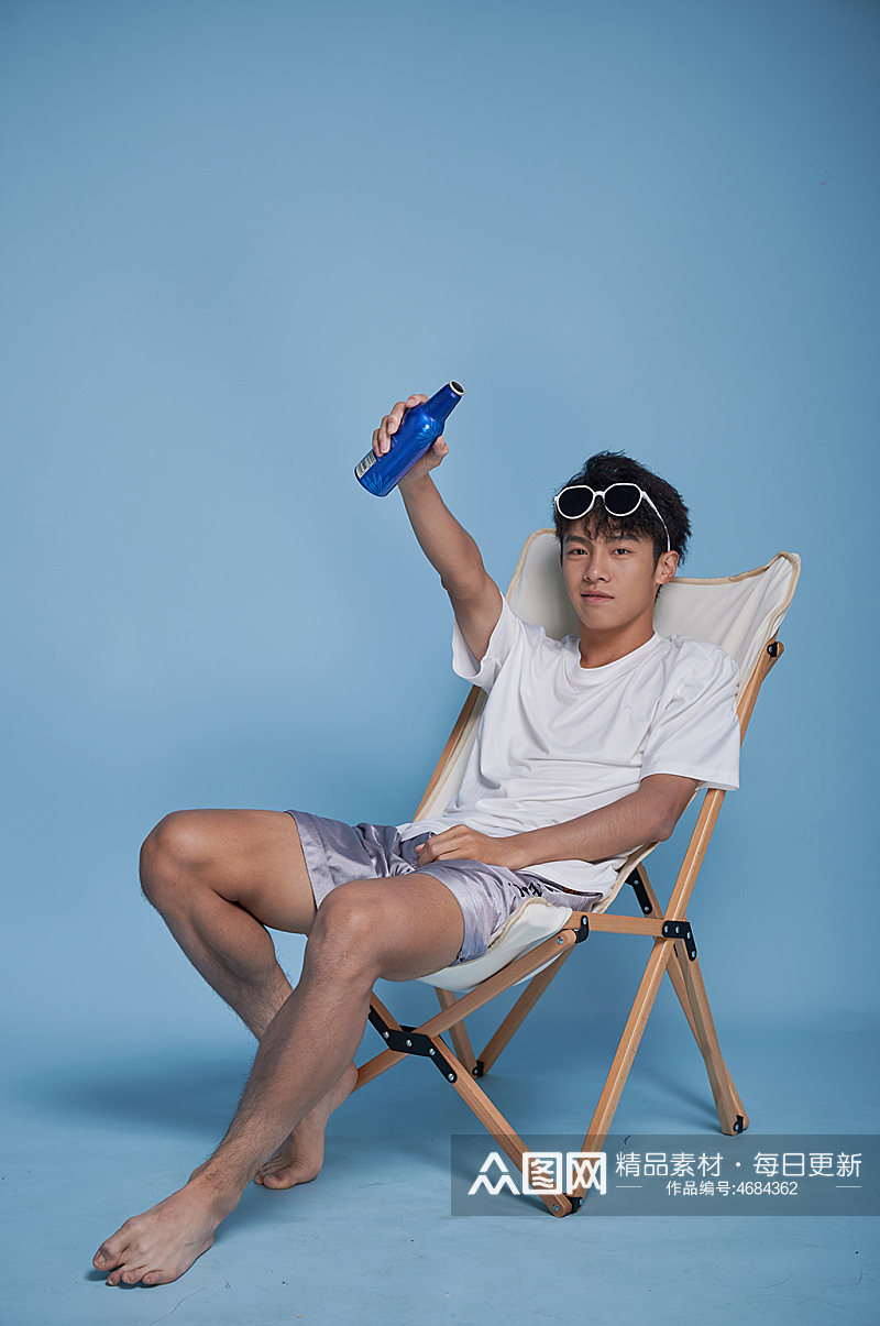 夏季男生喝啤酒泳装坐沙滩椅摄影图素材