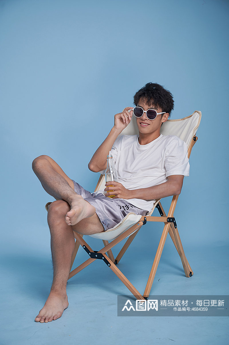 夏季男生喝饮料泳装坐沙滩椅摄影图素材