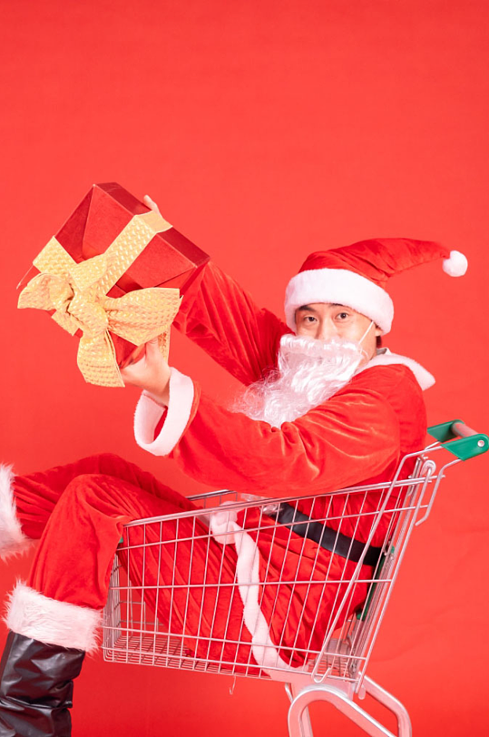 促销坐在购物车里送礼物的圣诞老人摄影图