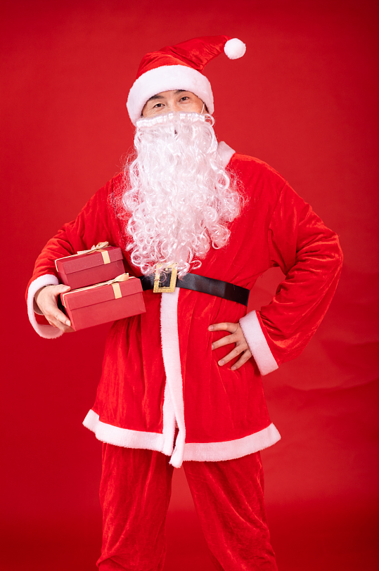 叉腰抱着礼物的圣诞老人摄影图