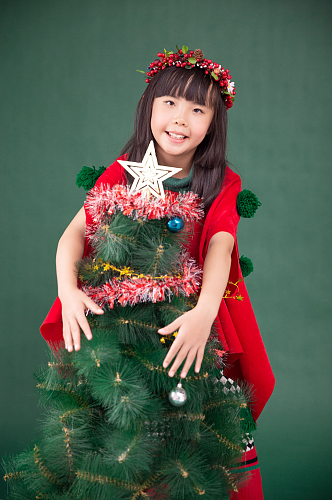 圣诞树旁可爱的小女孩摄影图
