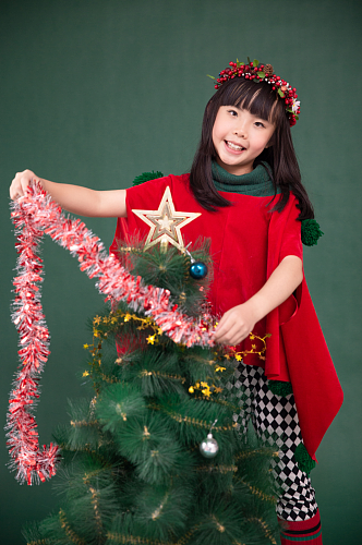 圣诞树旁可爱的小女孩摄影图