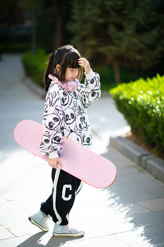 户外玩滑板的小女孩