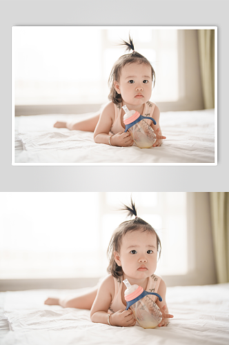 爬在床上拿奶瓶的小宝宝人物摄影图