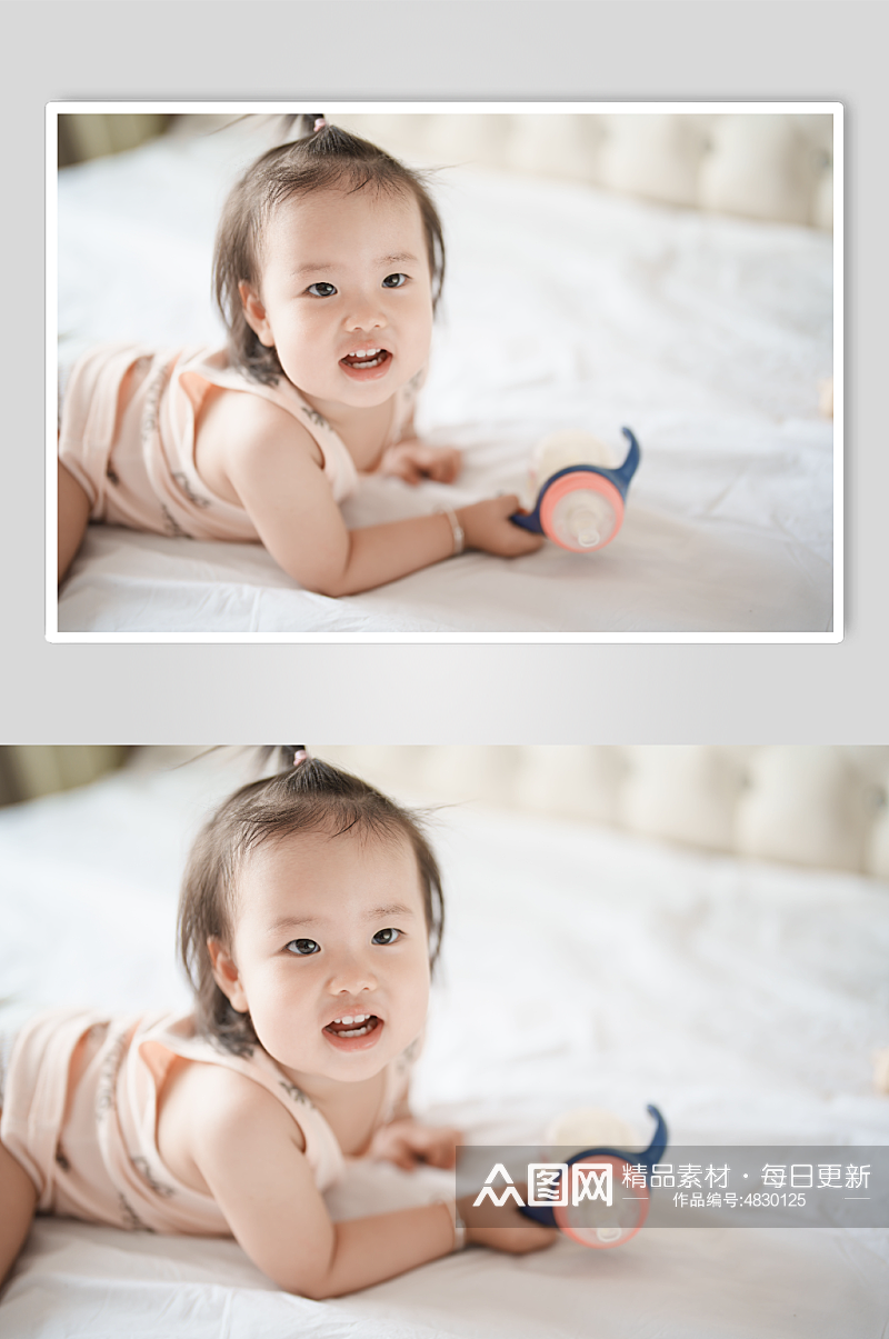 趴在床上手拿奶瓶的小宝宝摄影图素材