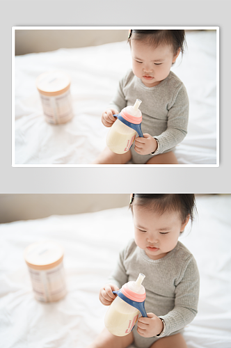 坐在床上喝奶粉的小宝宝摄影图