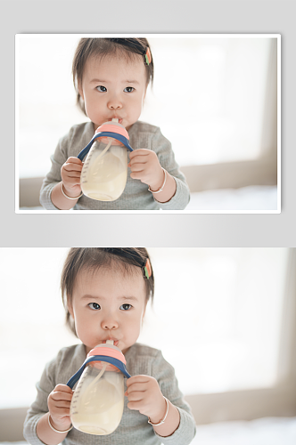 抱着奶瓶喝奶粉的小宝宝摄影图