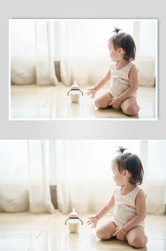 拿奶瓶玩耍的小宝宝摄影图