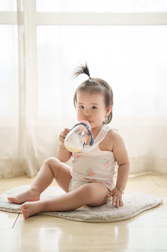 坐地上喝奶的婴幼儿摄影图