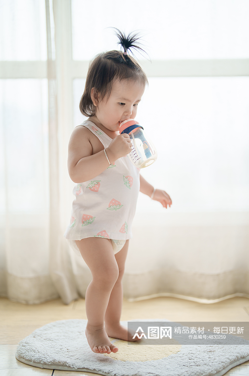 拿着奶瓶站着喝奶的婴幼儿摄影图素材