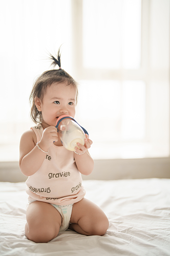 可爱的坐在床上喝奶粉的小宝宝人物摄影图