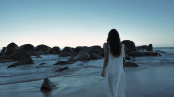 傍晚美女向海滩岸边上的巨石走去视频素材-众图网