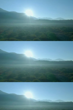 航拍蓝天阳光下群山之间的森林视频素材