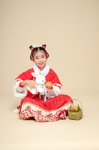 手持兔子玩偶水果兔年新年汉服儿童摄影图