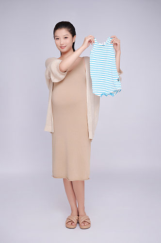手拿婴儿宝宝衣服服饰优雅孕妇人物摄影图