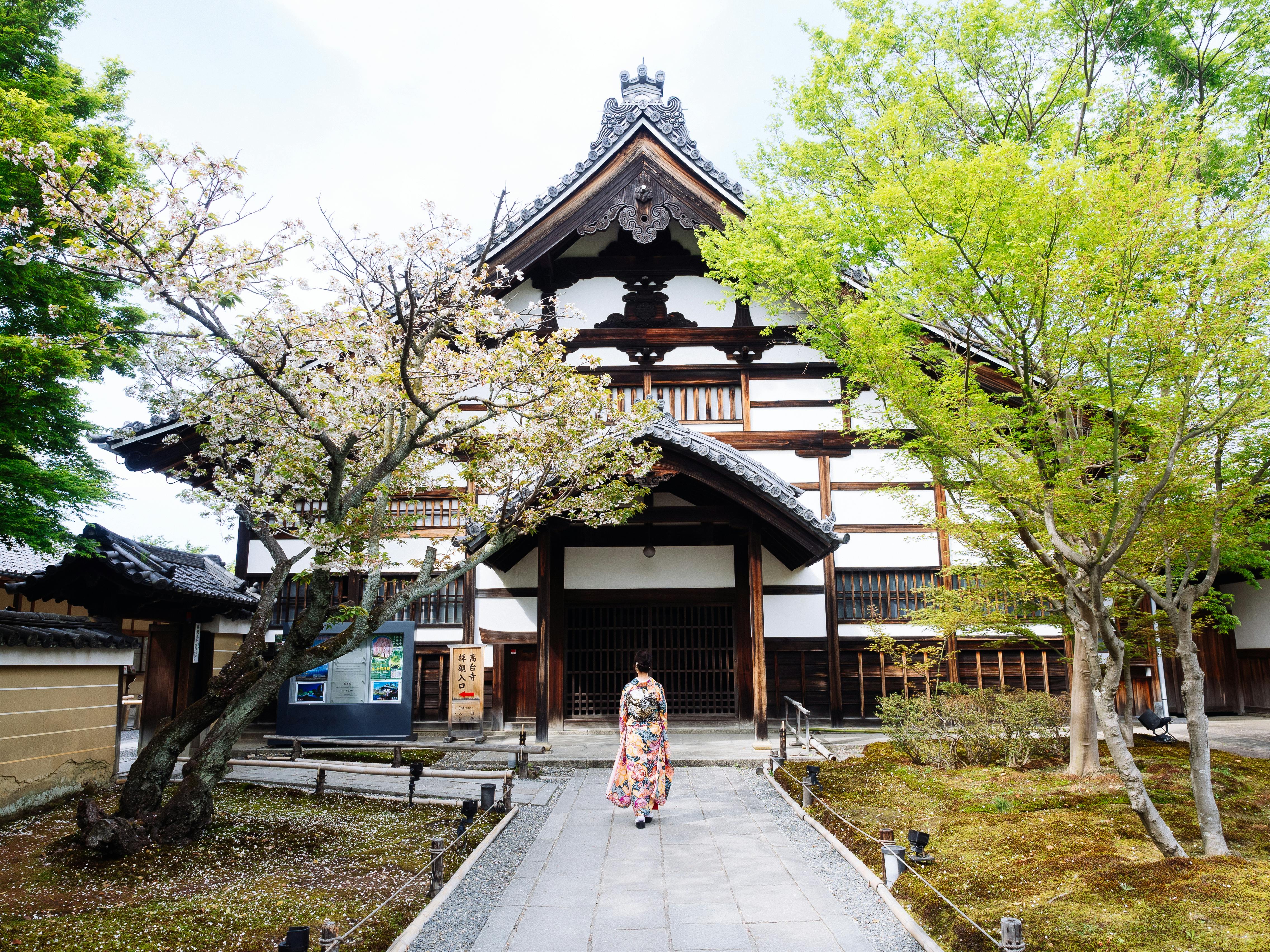 古建筑前樱花树下女子漫步素材