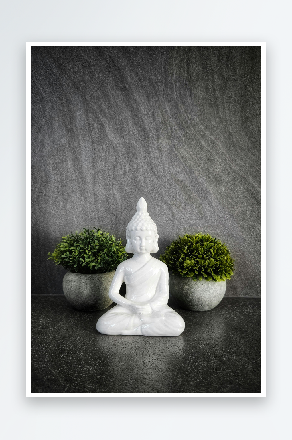 白色佛像静坐于绿植之间素材