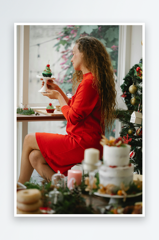 红裙女子圣诞装饰前手持甜点-众图网