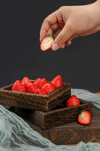 手拿草莓切面草莓果盘水果物品摄影图片
