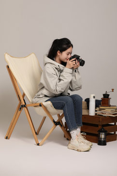 手拿相机冲锋衣坐在折叠椅户外露营摄影图片