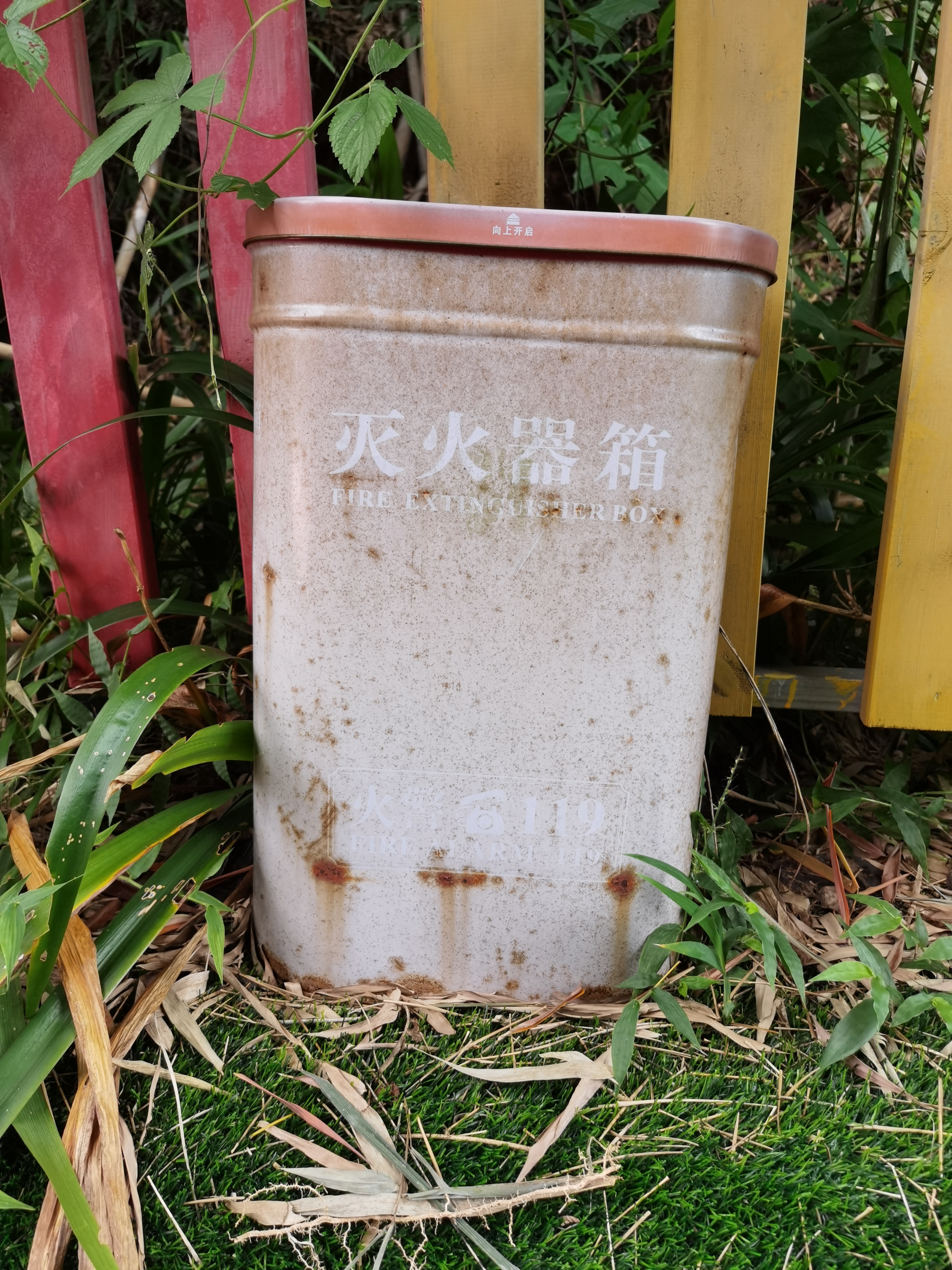 老旧灭火器靠于彩色栅栏边素材