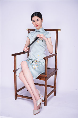 中式端正大气旗袍美女坐姿拿折扇商业摄影图