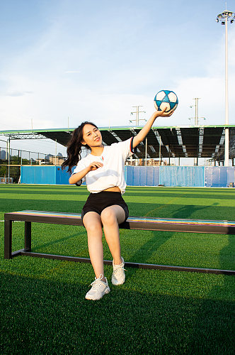 女生单人坐姿足球运动场人物摄影图照片