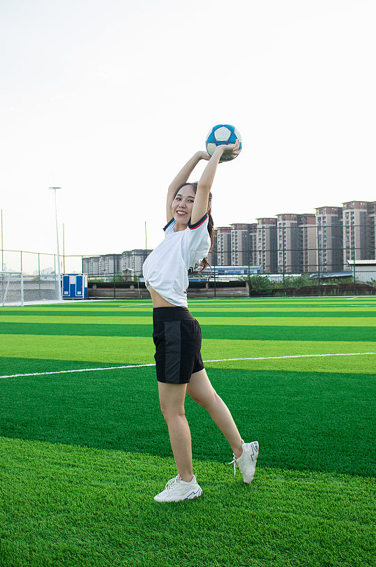 女生单人举球足球运动场人物摄影图照片