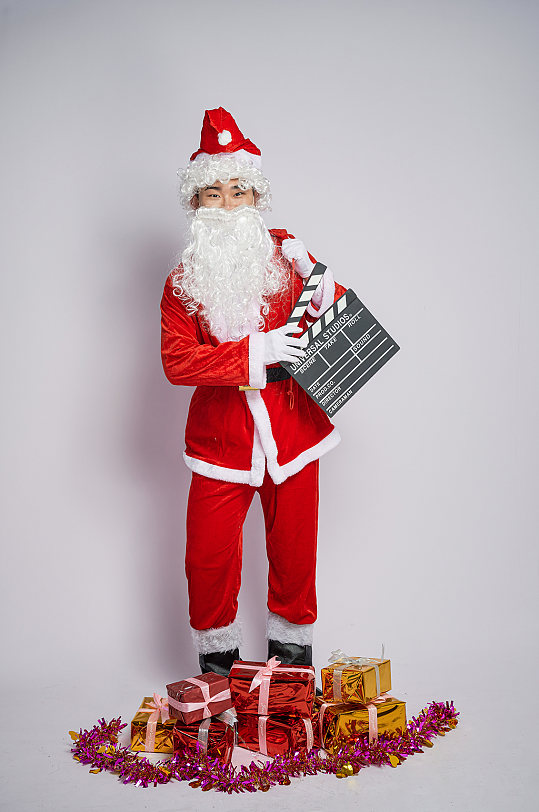 圣诞老人站立背礼物手拿场记板人物摄影图