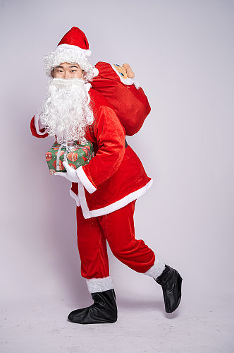圣诞老人背礼物袋手拿礼物盒人物摄影图