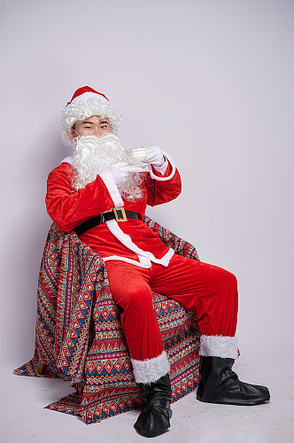 圣诞节圣诞老人坐椅子喝咖啡人物摄影图