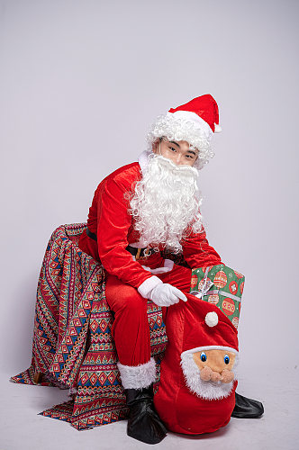圣诞节圣诞老人坐椅子掏礼物人物摄影图