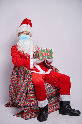 圣诞节圣诞老人坐椅子带口罩人物摄影图