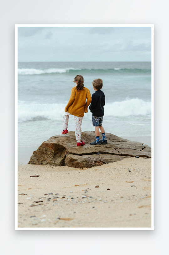 两个孩子站在海边岩石上-众图网