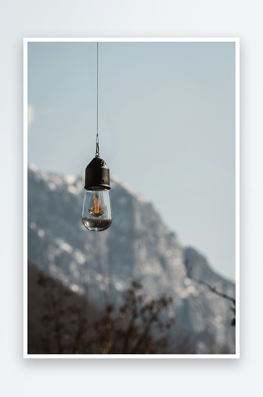 悬挂灯泡与雪山背景-众图网