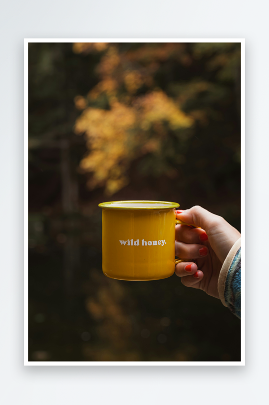 手持黄色杯子的秋日森林场景-众图网