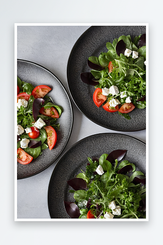 3个黑色陶瓷盘子里面有健康蔬菜沙拉西红柿